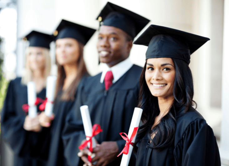 College students holding diplomas while wearing black cap and gowns diverse group of students